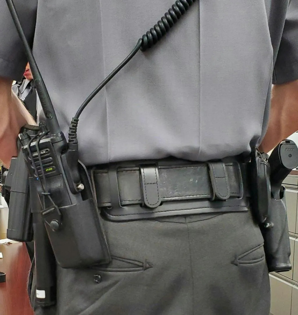 Police officer wearing loaded duty belt - back view showing gear weight on lower back