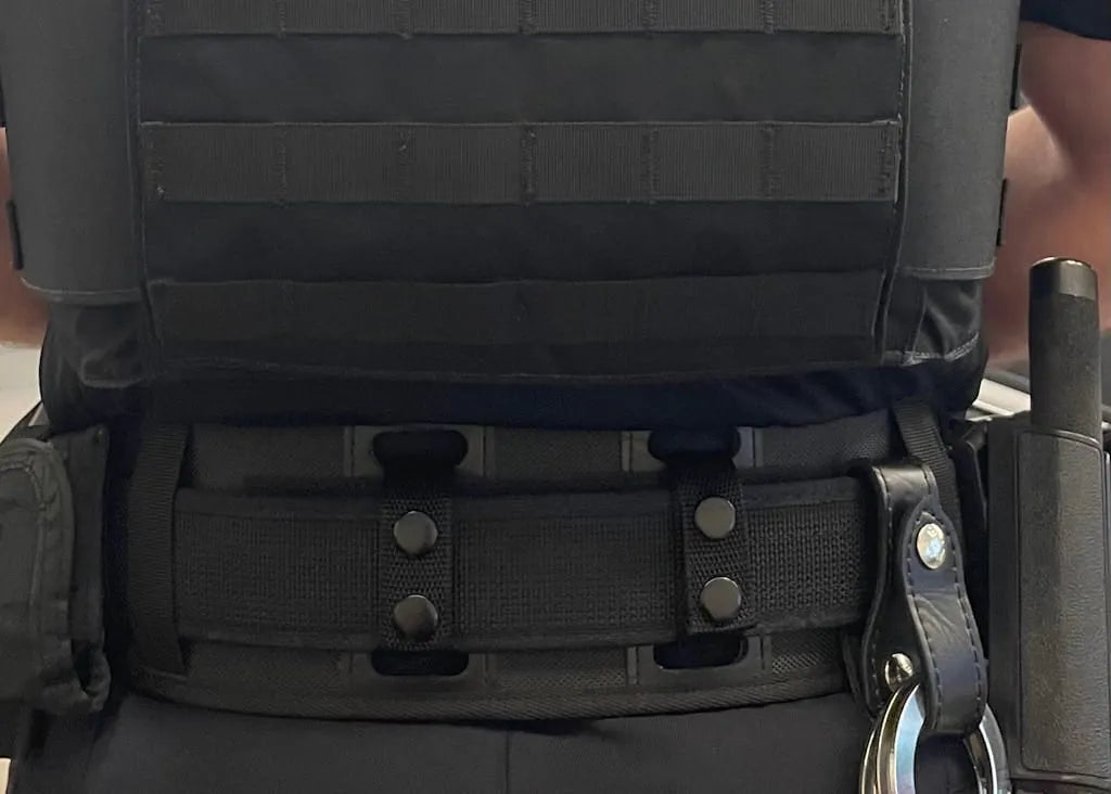 Officer wearing BackUpBrace nylon back support with vest carrier, handcuffs, and baton on duty belt