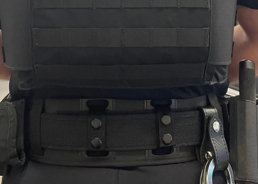 Officer wearing BackUpBrace nylon back support with vest carrier, handcuffs, and baton on duty belt