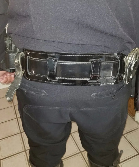Police officer wearing patent leather duty belt with BackUpBrace back support, handcuffs and expandable baton on duty belt